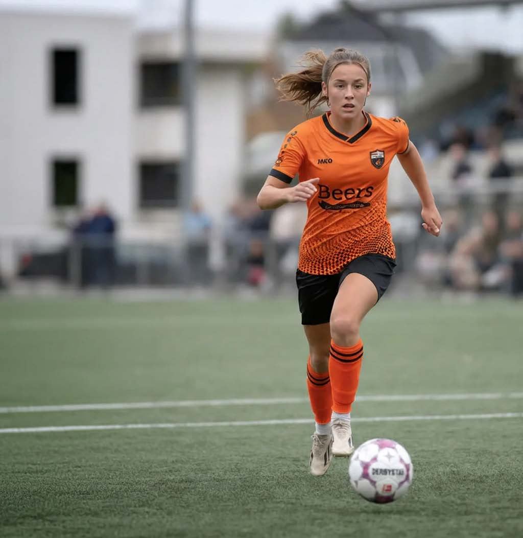 Een speelster van Jong Holland sprint met de bal aan de voet