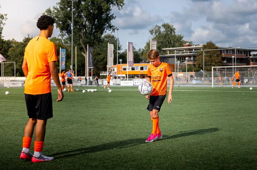 Fender houdt de bal hoog tijdens de warming-up, naast een speler van het eerste